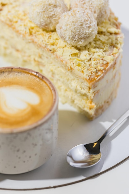 Coffee, spoon, a slice of cake on the plate on the white background.