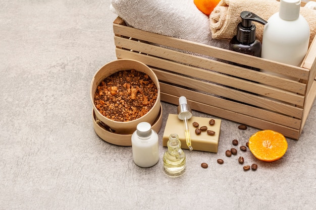 Coffee and tangerine spa concept. Towels, oil, scrub, soap, lotion. Natural ingredient, wooden box.