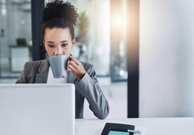 それからビジネスにコーヒーを飲みます彼女のオフィスで一杯のコーヒーを飲む魅力的な若い実業家のトリミングされたショット