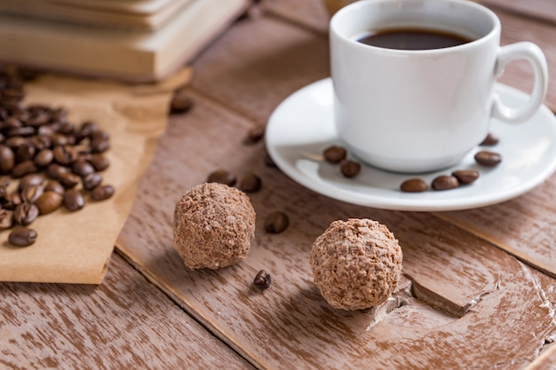 Coffee time break. Cup of freshly breved turk coffee, chocolate balls and book on wooden table