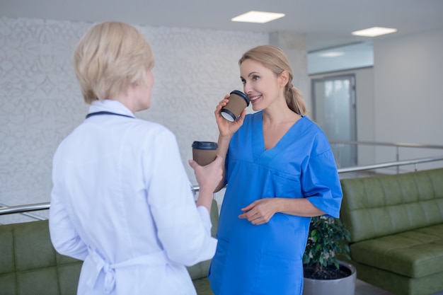 Coffee time. Two female doctors enjoying coffee, laughing, talking