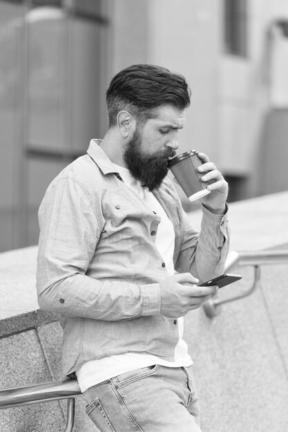 コーヒータイム メッセージを待っている 現代の生活 スマートフォンでコーヒーを飲む男性 携帯電話はいつも私と一緒です スマートフォンを使う男性 スマートフォンでソーシャルネットワークをサーフィンする エネルギー