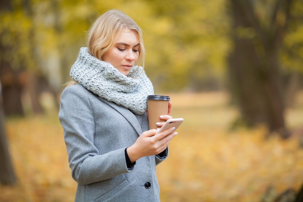 Coffee to go Jonge vrouw met koffie in het herfstpark