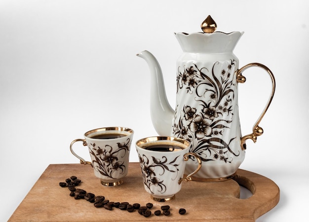 Coffee and two cups of coffee with beans on a wooden board, on a white background, angled top view.