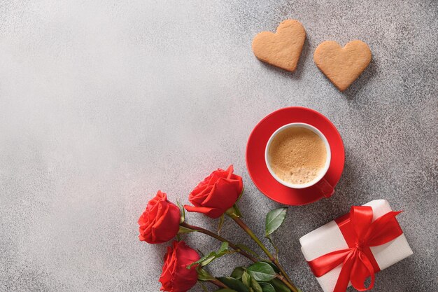 Coffee and two heart shaped cookies for valentines day bouquet of red roses and love gift