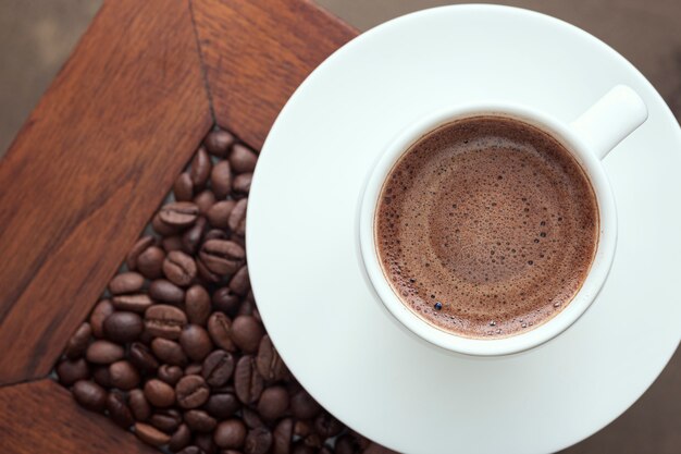 Coffee in a white cup and coffee beans on the table.