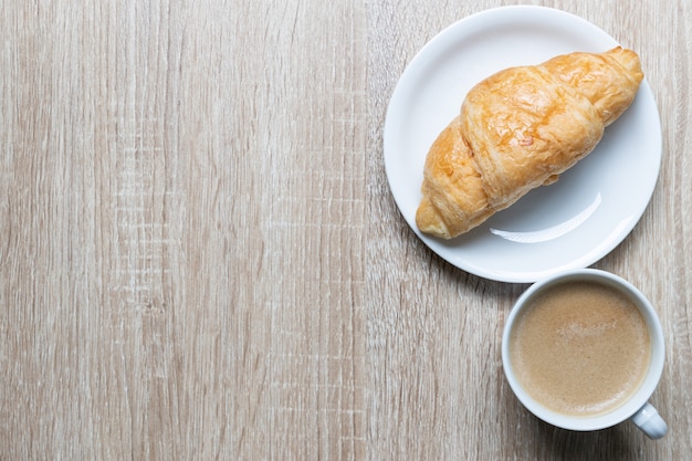 Coffee in white cup and croissants on wooden table, Breakfast concept