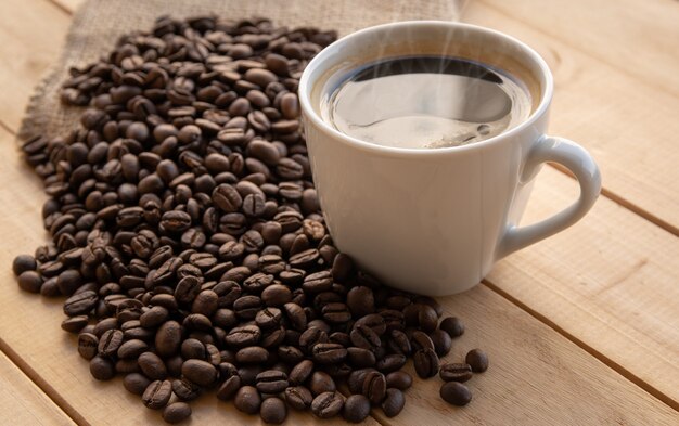 Coffee in white cup with beans on wooden table