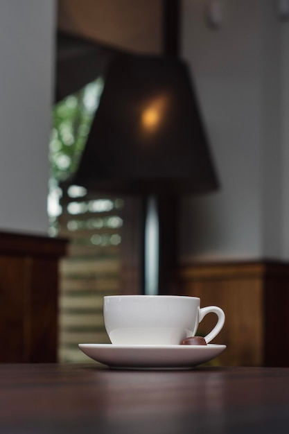 Кофе в белой чашке с конфетами на деревянном столе в ресторане