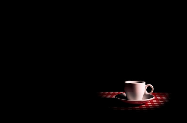 Photo coffee in a white cup with a saucer on a black background