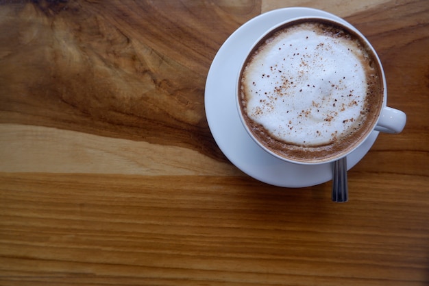 Coffee in white cup on wooden table.