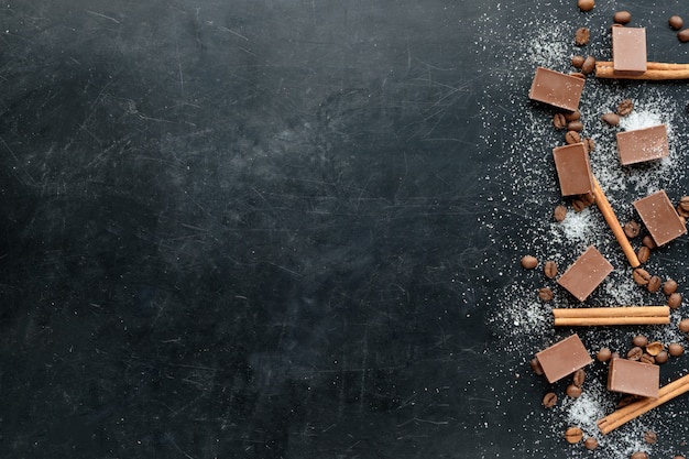 Coffee with chocolate shugar and cinnamon black background flat view copy space