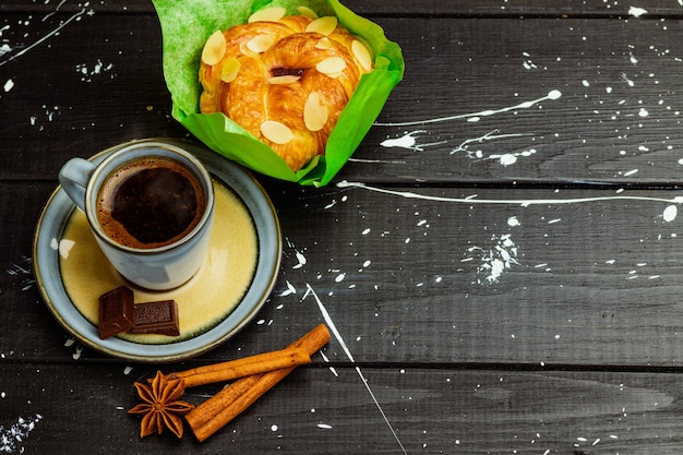 Coffee with cinnamon and cake on a black wooden table