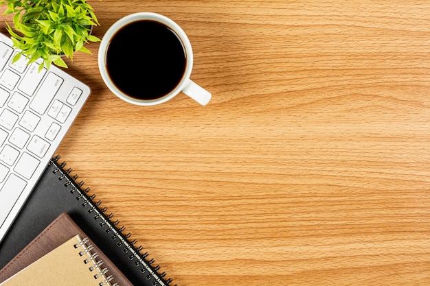 Coffee with computer keyboard, notebook on wooden office desk. - blank space for advertising text.