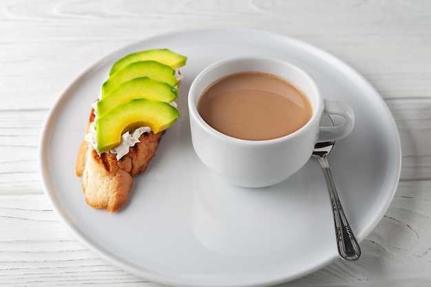 Coffee with cream and cream cheese sandwich with avocado