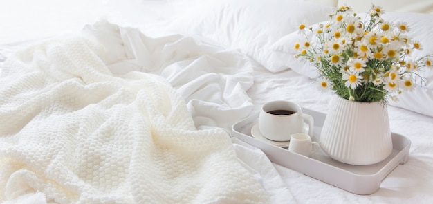 Coffee with flowers on a tray in bed