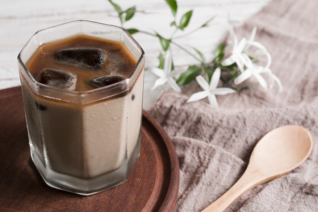 Coffee with ice cubes in glass and flowers