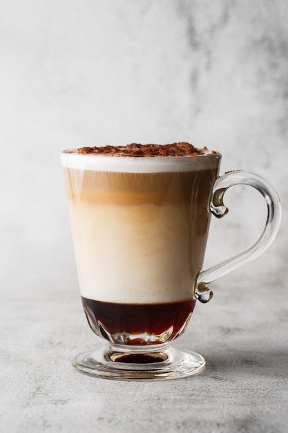 Coffee with Irish whiskey and whipped cream in glass isolated on bright marble background. Overhead view, copy space. Advertising for cafe menu. Coffee shop menu. Vertical photo.