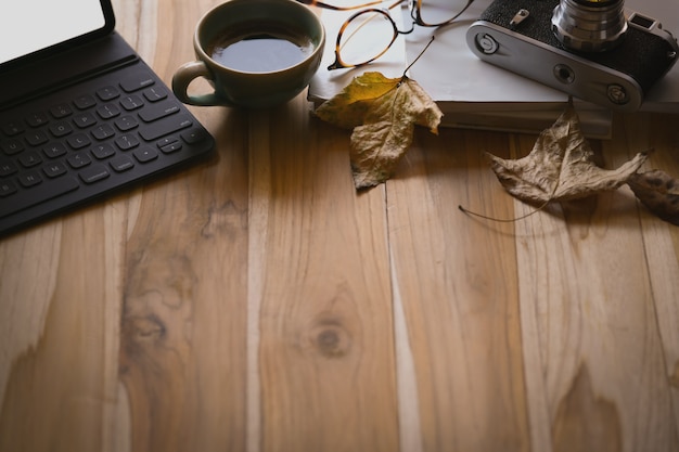 Coffee with keyboard tablet, autumn leaves on wooden table and copy space