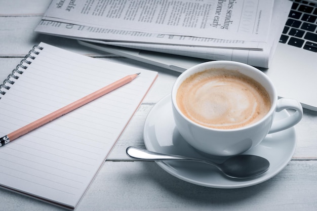 흰색 나무 테이블 위에 노트북, 신문, r 연필, 안경이 있는 커피. 비즈니스 개념입니다.