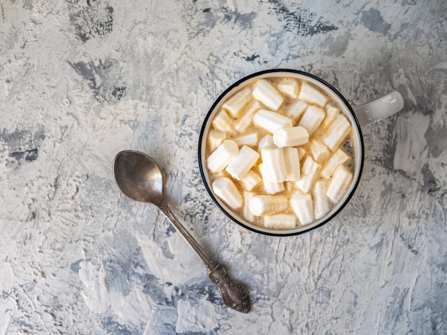 Coffee with marshmallows in a white mug and a teaspoon