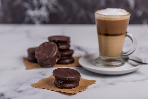 Coffee with milk and Dulce de Leche alfajor with chocolate sweets