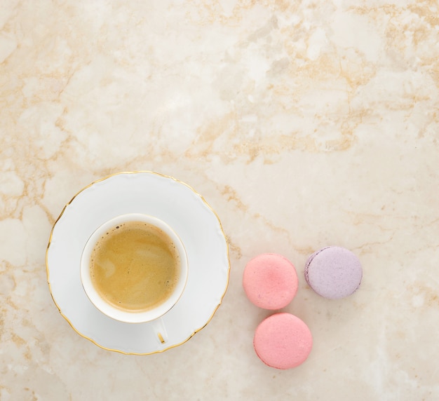 Coffee with milk and French macarons on a marble