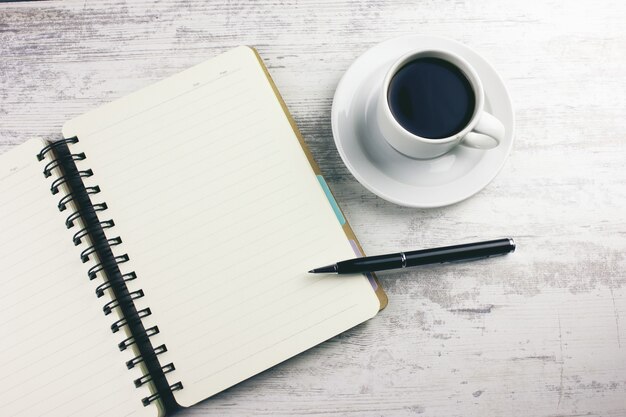 Coffee with a notebook and pens on the table