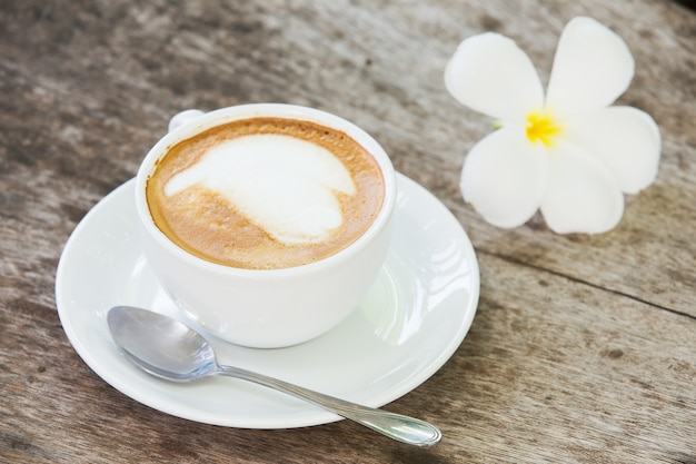 Foto caffè con il modello in una tazza bianca su fondo di legno