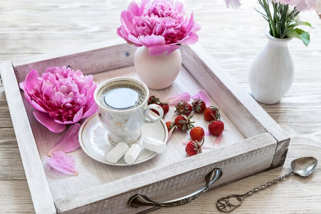 Coffee with pink flower and strawberry on wooden table