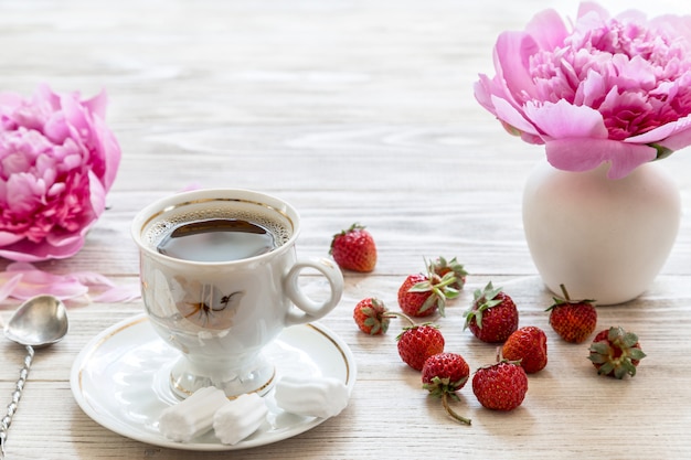 ピンクの花と木製のテーブルにイチゴのコーヒー