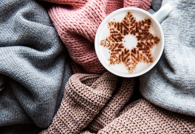 Coffee with a snowflake pattern on a warm knitted sweaters  surface