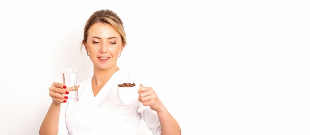 Foto caffè con acqua la nutrizionista femminile tiene in mano una tazza di chicchi di caffè e un bicchiere d'acqua su sfondo bianco