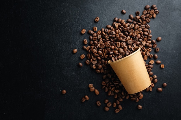 coffee or zero waste concept. coffee beans in paper cup on dark background.