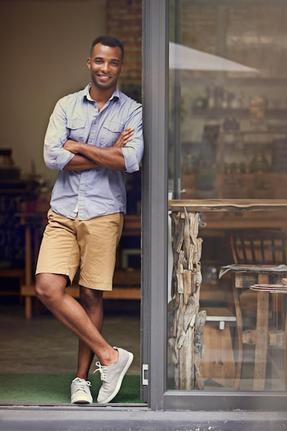 Foto coffeeshop zwarte man en portret van de eigenaar van een klein bedrijf aan de deur van het opstarten van de detailhandel ondernemer mannelijke persoon en manager van een professionele winkel met een glimlach voor de trots en doelen van de servicecarrière