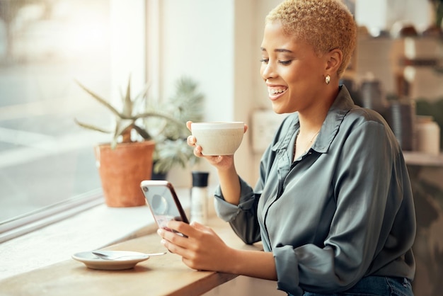 Coffeeshoptelefoon en sociale media met een zwarte klant die drinkt terwijl ze een sms typt bij een raam Internetcafé mobiel of communicatie met een vrouw die geniet van een drankje in een restaurant