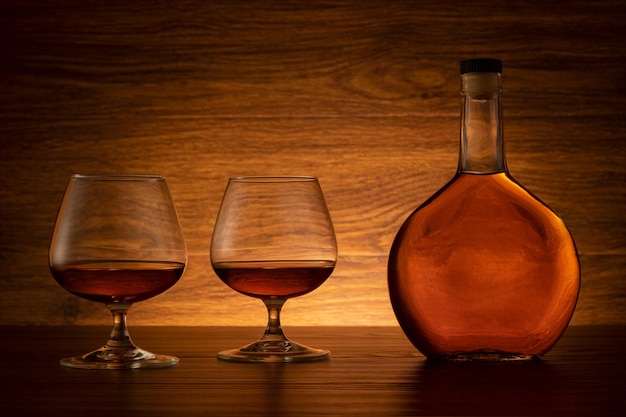 Cognac bottle with two glasses on wooden background