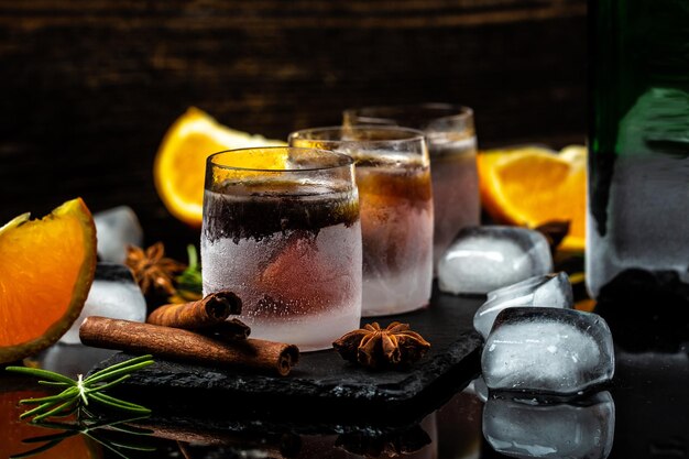 Cognac or herb liqueur with cinnamon and oranges on a dark background Seasonal holidays concept