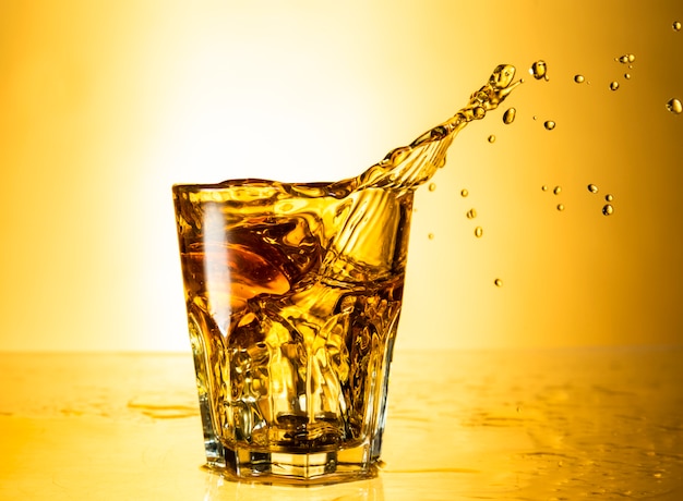 Cognac in a splash glass isolated on background with reflection