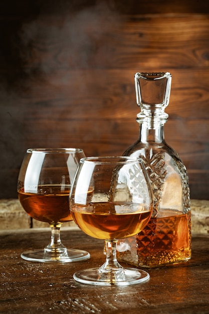 Photo cognac or whiskey in glasses on rustic backgrpund