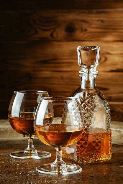 Photo cognac or whiskey in glasses on rustic table