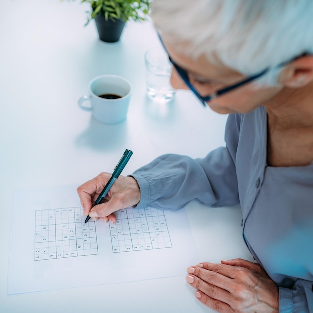 Foto allenamento cognitivo donna anziana che risolve enigmi di sudoku