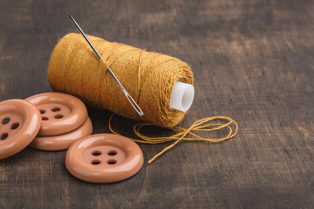 Coil is yellow thread and buttons on wooden table.