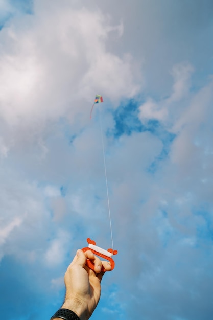 Coil with a rope with a kite flying in the sky in a male hand