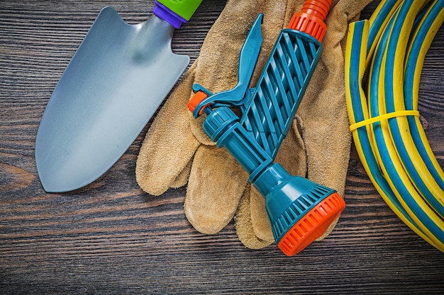 Спиральная лопата руки защитных перчаток садового резинового шланга на концепции сельского хозяйства деревянной доски.