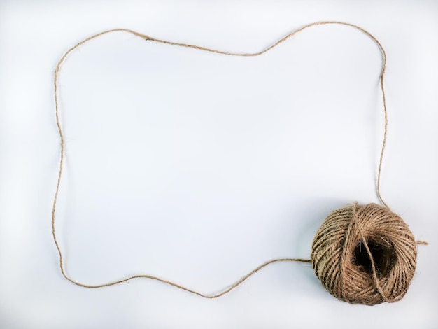 Foto corda grezza arrotolata fatta di varie fibre in una lunga corda è tesa in una cornice con uno spazio per inserire il testo nel mezzo per marrone artigianato sfondo bianco isolato girato in studio