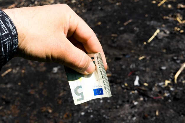 Coin and banknotes on black hot coal among ashes currency devaluated finance and business concept