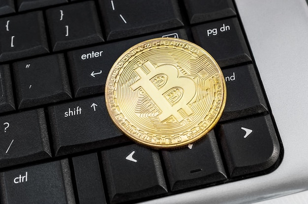 Coin of bitcoin on laptop keyboard Close up Business and ecommerce concept