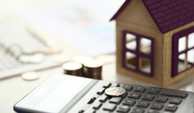 Coin lay on calculator house model on office desk