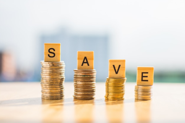 Coin of money on wooden table and text SAVE with blur background.